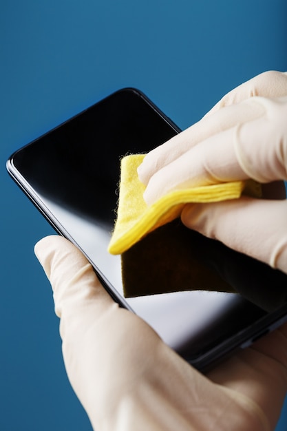 Limpar a tela do celular com um pano amarelo e luvas de borracha.