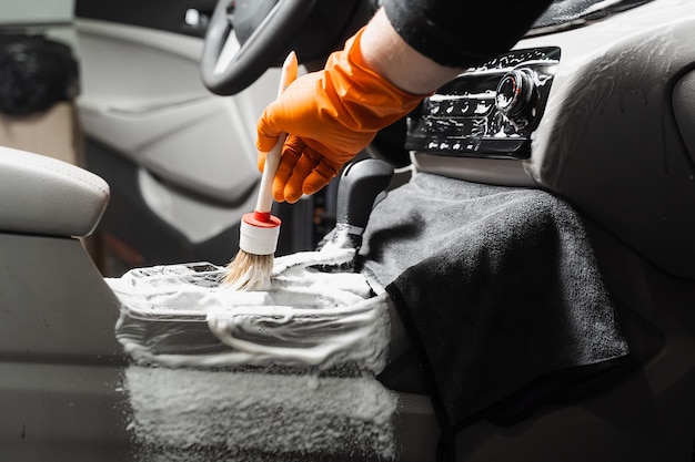 Limpeza a seco com escova de caixa de câmbio e painel em carro Serviço de detalhamento automotivo Limpeza de elementos individuais do interior em automóveis