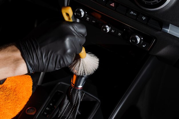Foto limpeza a seco com escova de caixa de velocidades e painel no carro serviço de detalhamento automático limpeza de elementos individuais do interior de couro preto em auto