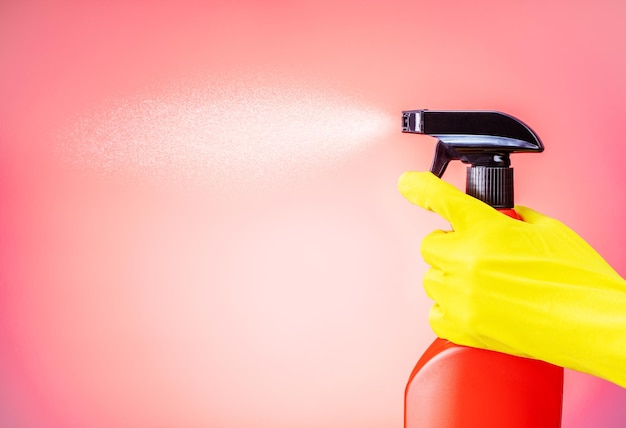 Limpeza com detergente em spray Mão feminina na luva amarela pulverizando spray de limpeza