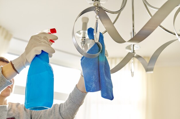 Limpeza da casa, close-up das mãos com detergente de pano, lâmpada de limpeza e polimento, lustre