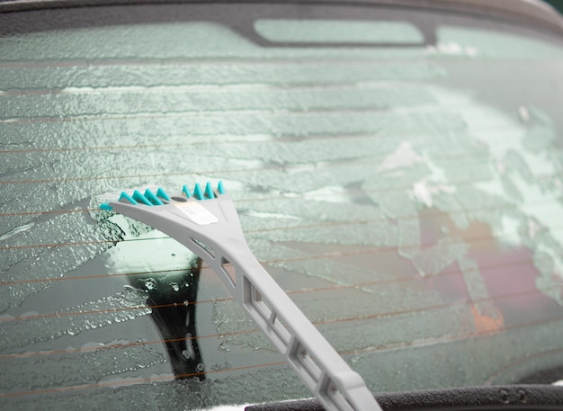 Limpeza da janela do carro de neve e gelo em uma manhã de inverno