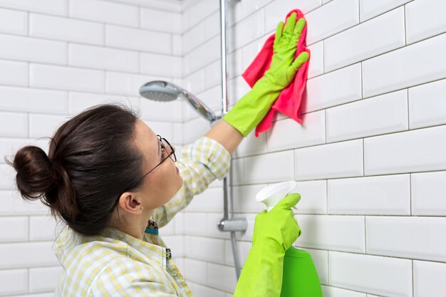 Limpeza do banheiro, dona de casa lavando a parede de ladrilhos brancos com detergente e pano, copie o espaço. Conceito de higiene, pureza, limpeza