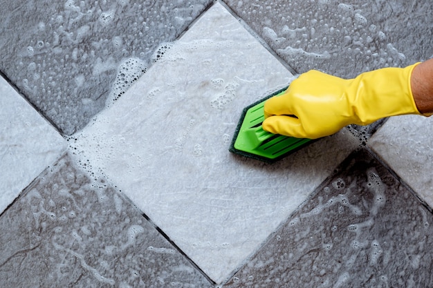 Limpeza do piso de cerâmica com uma esfregona de plástico de cor verde.