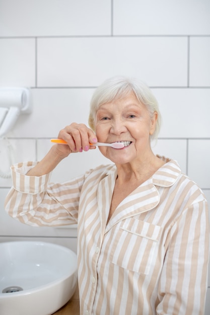 Limpeza dos dentes. mulher idosa de pijama limpando os dentes