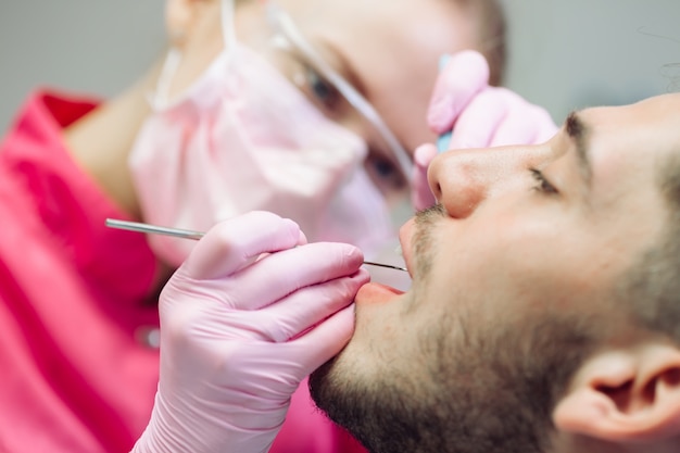 Limpeza profissional dos dentes, o dentista limpa os dentes de um paciente do sexo masculino.