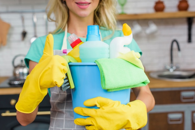 Foto limpiador con herramientas y productos de limpieza que muestran gesto de pulgar