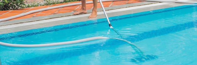 Limpiador del hombre de la piscina con una camisa azul con equipo de limpieza para piscinas soleadas