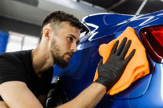 Limpiador hombre trabajador cuerpo seco coche después de lavar automóvil Mano coche secado con microfibra en detalle auto servicio