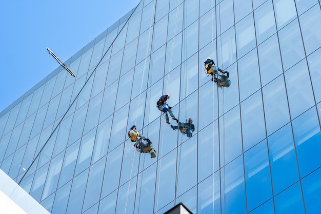 Los limpiadores de ventanas están trabajando en la fachada del edificio de oficinas de gran altura