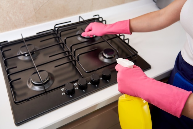 Limpiar una estufa de gas con utensilios de cocina, conceptos del hogar o higiene y limpieza.
