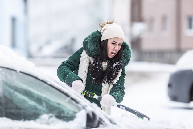 Limpiar la nieve del automóvil en un día de invierno como un duro trabajo matutino después de la tormenta de nieve.