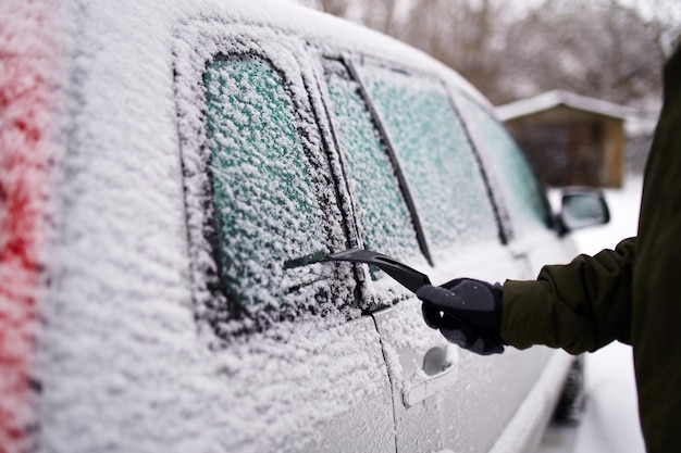 Limpiar la ventana trasera del coche de nieve con un raspador de