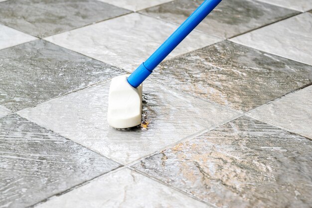 Foto limpiar el piso de baldosas con un cepillo para pisos de mango largo