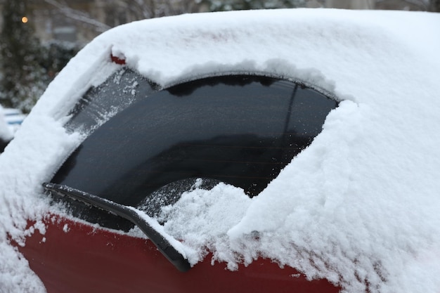 Limpiar la ventana del coche de la nieve al aire libre en el día de invierno