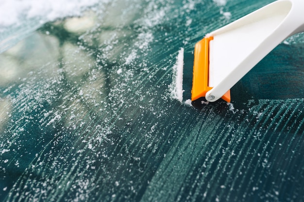 Limpiar el vidrio del automóvil del hielo con un raspador