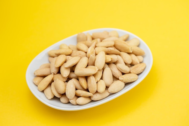 Limpie las almendras en un plato blanco pequeño sobre amarillo