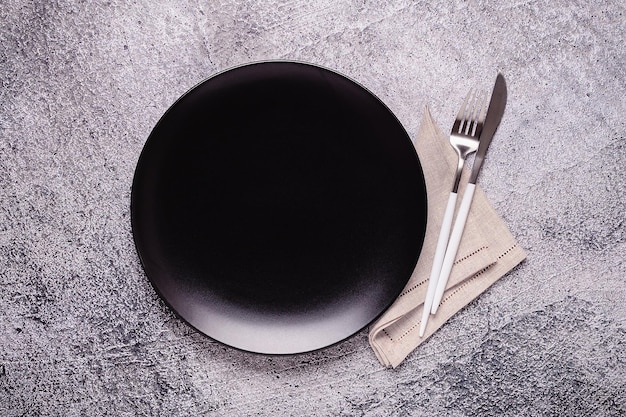 Limpie el plato negro vacío con cubiertos