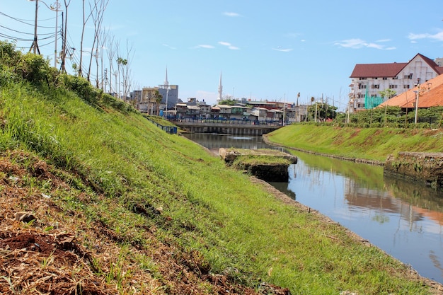 Limpie el río urbano con hierba verde en las orillas