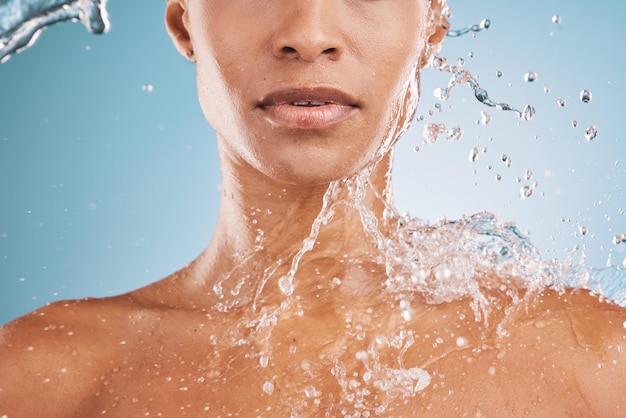 Limpieza de agua y ducha con una mujer negra modelo en estudio sobre un fondo azul para hidratación o higiene Relájese, bienestar y lujo con un toque de agua en una mujer en el baño para el cuidado de la piel