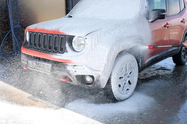 Limpieza de autos Auto rojo en la espuma en el lavado de autos