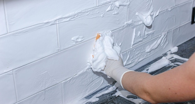 limpieza de azulejos de cerámica de cocina con un limpiador de esponja