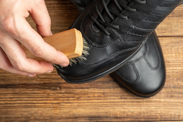 Foto limpieza de botas de cuero negro pulido con cepillo y betún para calzado