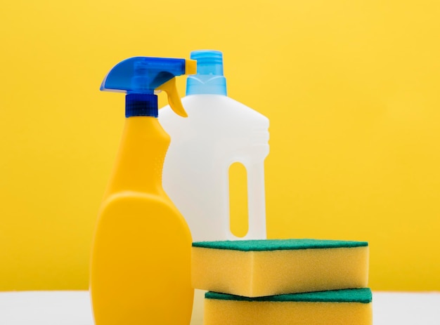 Limpieza de botellas de spray y paños contra un fondo amarillo brillante