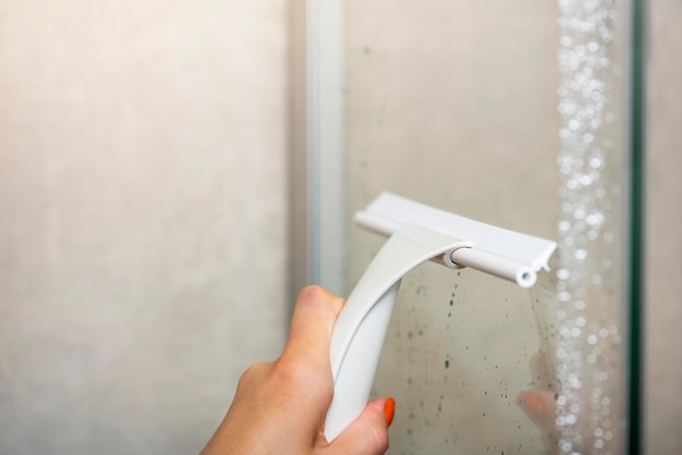 Limpieza de la cabina de ducha limpieza de la pared de cristal de la cabina de ducha con un raspador de cristal limpieza del