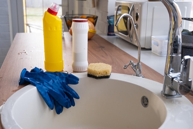 Limpieza de la cocina Los guantes de esponja de polvo seco de detergente están en el fregadero Decoración festiva en el interior acogedor de la cocina blanca de la casa