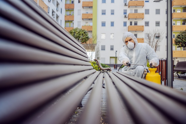 Limpieza y desinfección en el exterior alrededor de los edificios, la epidemia de covid-19. equipos de sesión para los esfuerzos de desinfección. prevención de infecciones y control de epidemias. e traje y máscara.