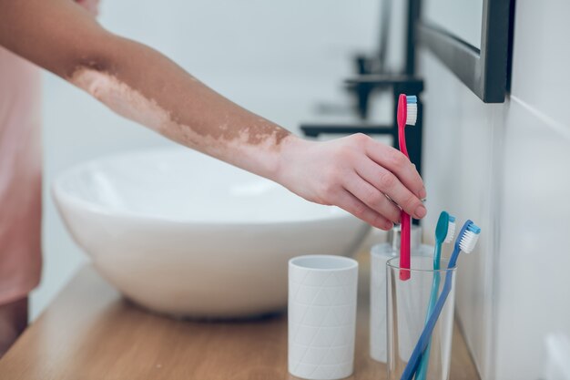 Limpieza de dientes. Imagen de una mujer poniendo el cepillo de dientes en el cristal