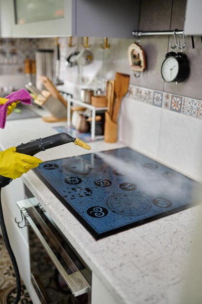 Foto limpieza de una elegante estufa eléctrica con un generador de vapor el vapor limpia la superficie de la suciedad cocina blanca limpieza en el apartamento