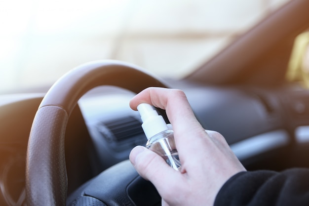 Limpieza del interior del vehículo y pulverización con líquido desinfectante. Desinfección del volante y manijas del automóvil. Coronavirus, protección Covid-19. Desinfección del vehículo dentro,