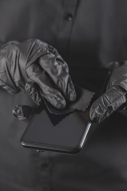 Foto limpieza de la pantalla del teléfono inteligente con un concepto de higiene personal de limpieza todo negro
