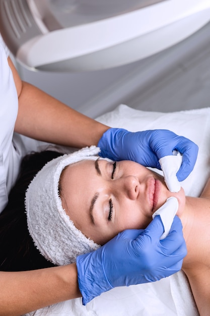 Limpieza de puntos negros en la cara de la mujer durante el tratamiento facial en la clínica de belleza de lujo.