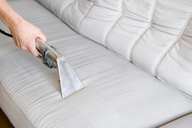 Foto limpieza química profesional concepto de limpieza el hombre limpia el sofá en la habitación de cerca