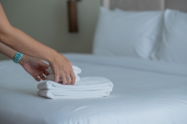 limpieza de la toalla de baño del hotel en la cama blanca persona de servicio de habitaciones