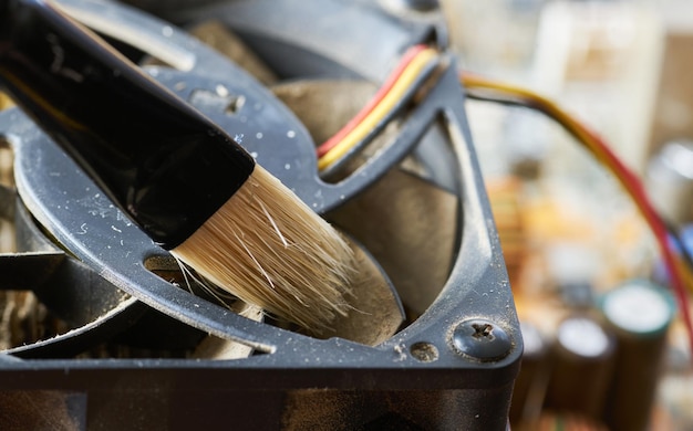 Limpieza del ventilador del procesador de la computadora de escritorio sucio del polvo con un cepillo especial de cerca