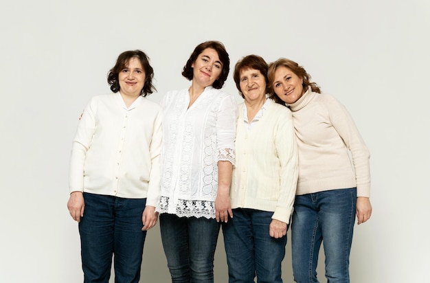 Una linda abuela se sienta en un sillón con sus hijas y se divierte en un fondo blanco. abuela con sus hijas. pensionista con mujeres de fondo blanco