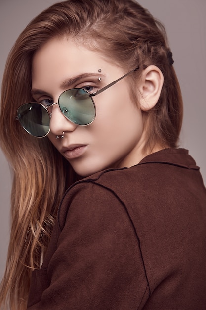 Linda adolescente en chaqueta de moda y gafas de color