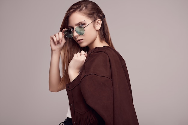 Linda adolescente en chaqueta de moda y gafas de color