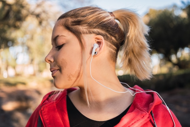 Linda adolescente com uma verruga no rosto, ouvindo música com fones de ouvido.