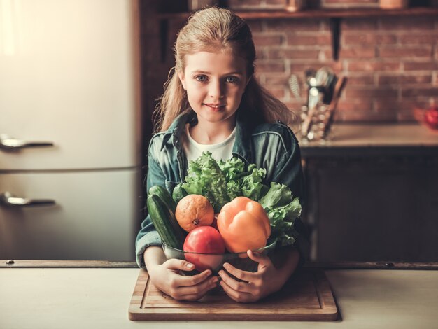 Linda adolescente está sosteniendo un tazón con verduras.