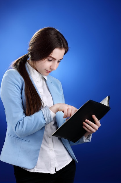 Linda adolescente lendo sobre fundo azul