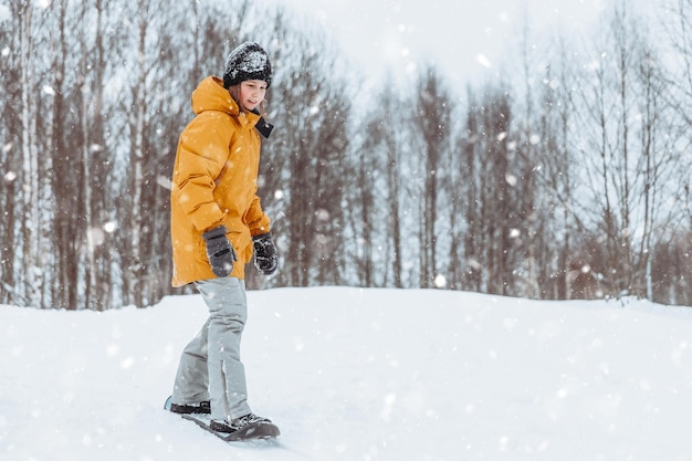 Linda adolescente monta un patín de nieve en un parque de invierno estilo de vida saludable