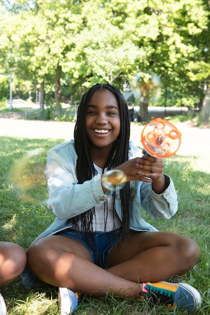 Foto linda adolescente negra brincando com bolhas de sabão