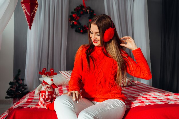 Linda adolescente ouvindo música em seus fones de ouvido vermelhos e fofos em uma sala decorada para o natal