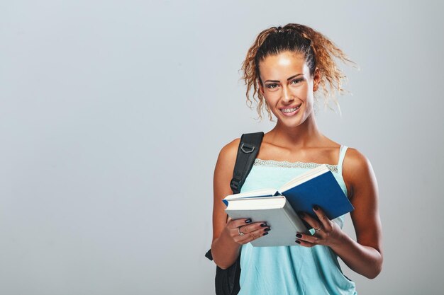 Foto linda adolescente sorridente com mochila está lendo um livro.