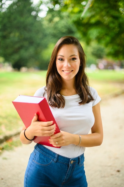 Foto linda aluna segurando um livro ao ar livre